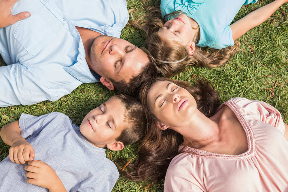 Family Lying on Grass Closing Eyes